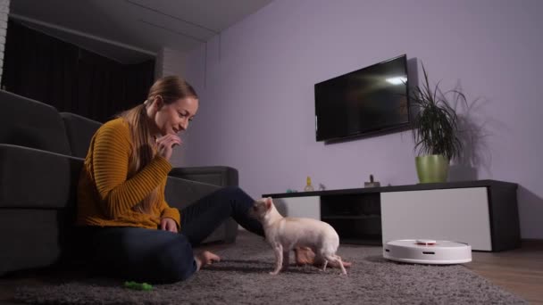 Radosna kobieta bawiąca się ze zwierzakiem zamiast sprzątać - Materiał filmowy, wideo