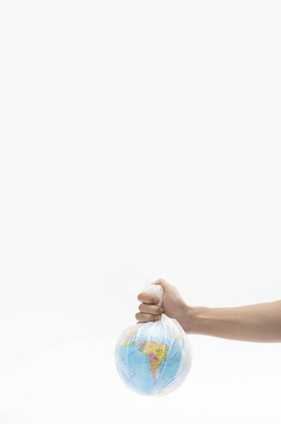 A vertical shot of a hand holding the globe in a plastic bag - environmental concept - Φωτογραφία, εικόνα