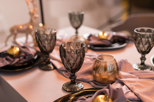 Primer plano de la mesa navideña festiva con copas de vino vacías y plato negro con granate dorado. Concepto de Navidad y Año Nuevo - Foto, imagen