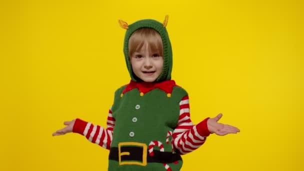 Niña impactada en traje de ayudante de Navidad elfo de Santa. Niño mirar a la cámara y hacer una pregunta lo que - Imágenes, Vídeo