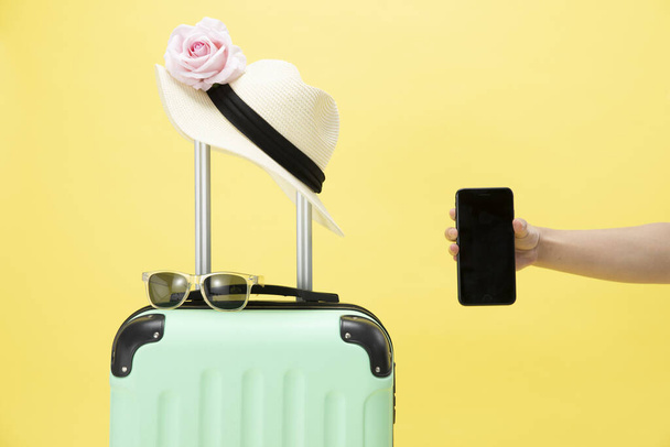 A top view of a suitcase, sunglasses, phone and hat on a yellow background - vacation concept - 写真・画像