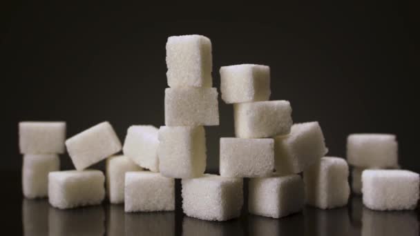 Pyramide aus weißen Zuckerwürfeln isoliert auf dunklem Hintergrund. Archivmaterial. Nahaufnahme von weißen Zuckerstücken, Konzept von Diabetes und Fettleibigkeit. - Filmmaterial, Video