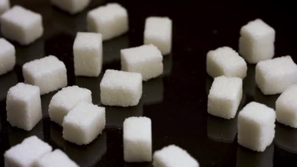 Close up of hand brushing the half of sugar cubes off the table, giving up on eating candy and sweets. Stock footage. Pieces of white sugar isolated on black background. - Footage, Video