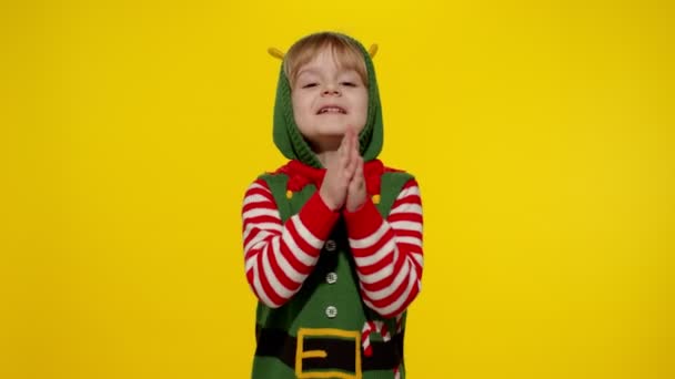Il bambino in costume di Babbo Natale elfo aiutante implora, prega su regali durante Anno nuovo. Mantiene unite le palme - Filmati, video
