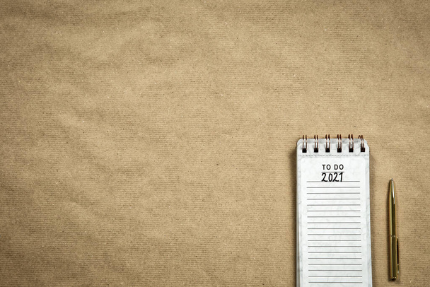 Planning New Year goald on empty notepad in the year 2021, top view on brown background texture, top view copy space, space for text modern design - Photo, Image