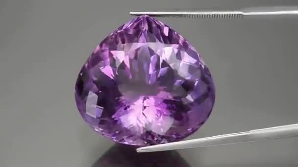 amatista púrpura natural sobre el fondo gris - Imágenes, Vídeo