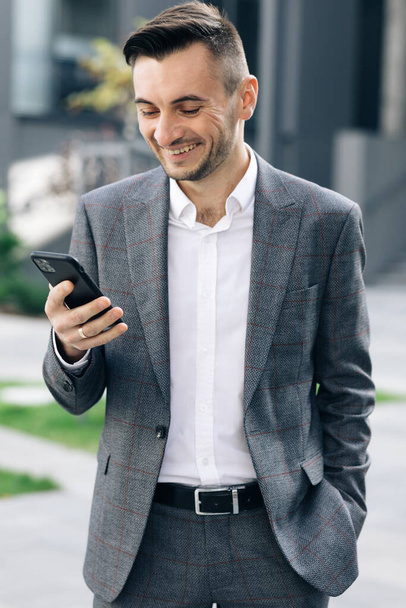 Footage from Outside: Handsome bearded businessman using mobile phone. Young man texting messages, cheating on his smartphone near business center. Vertical Screen Orientation. - Fotografie, Obrázek