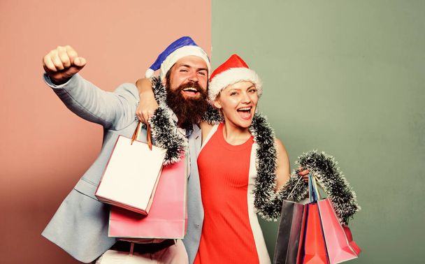 Merry christmas. Cheerful couple Santa hats hold paper bags. Buy gifts. Happy new year. Family shopping. Join celebration. Prepare presents in advance. Man and woman shopping. Christmas shopping - Foto, Imagem