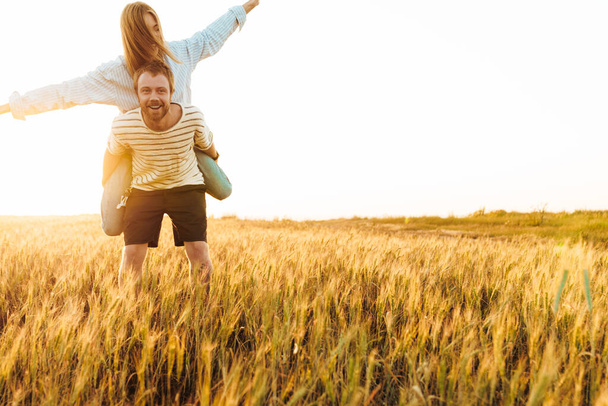 Image of amazing positive loving couple walking together outside at the field and having fun - Foto, Imagem