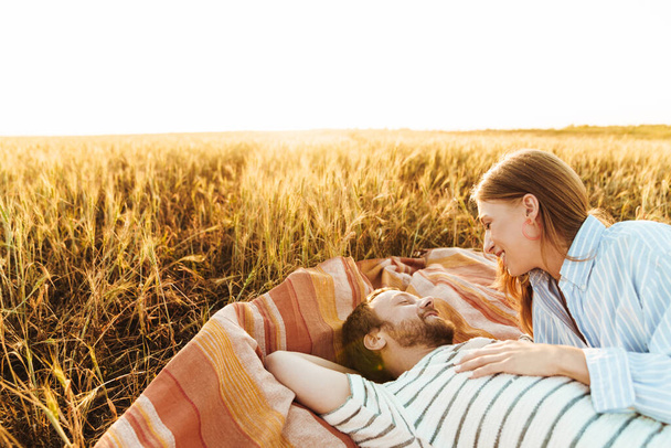 Image of a young happy cheery loving couple lying together outside at the field - Valokuva, kuva