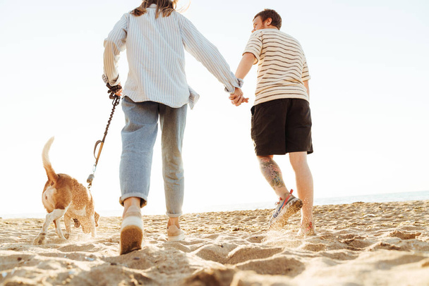 Image of a young family loving couple playing with dog outside at the beach - Foto, Imagen