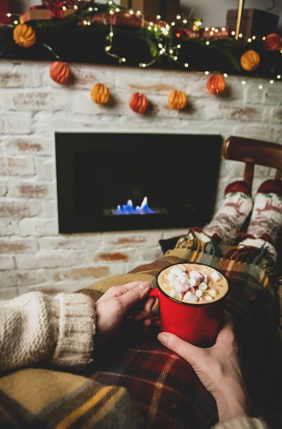 Woman with cup of coffee sitting near a firepalce at home  - Foto, Imagen
