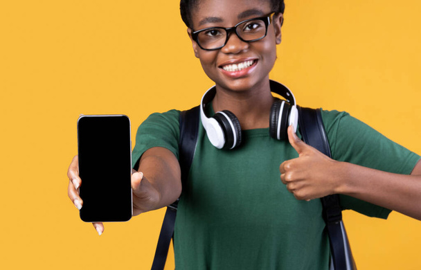 Black Female Student Showing Smartphone Screen Gesturing Thumbs-Up, Yellow Background - Photo, Image
