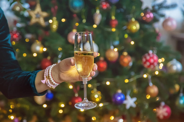 クリスマスツリーの背景に手にシャンパン。選択的フォーカス。休日. - 写真・画像