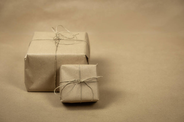 два подарункові пакети, загорнуті звичайним коричневим папером і мотузкою і коричневим папером текстури фону, ретро подарункова коробка. присутня концепція
 - Фото, зображення