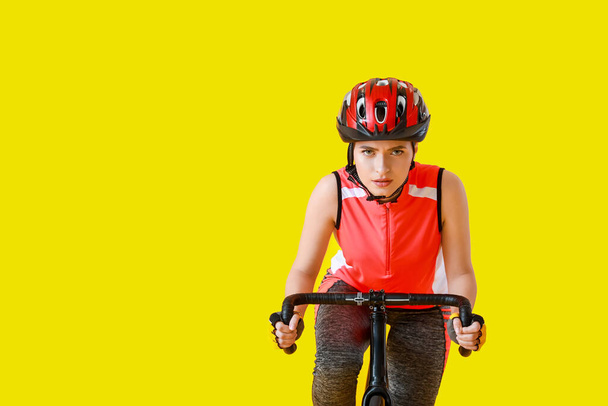 Female cyclist riding bicycle on color background - Photo, Image