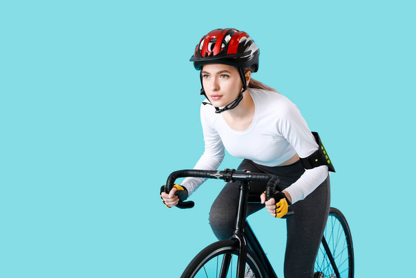 Vrouwelijke fietser rijden fiets op kleur achtergrond - Foto, afbeelding