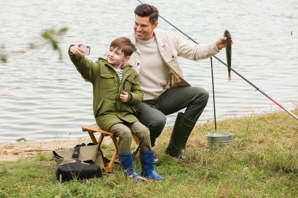 Little boy and his father taking selfie while fishing on river - Zdjęcie, obraz