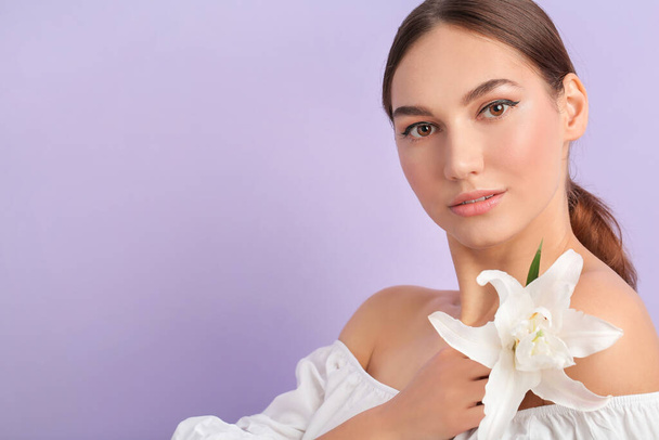Beautiful young woman with fresh lily on color background - Foto, imagen
