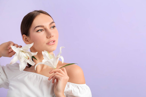 Schöne junge Frau mit frischen Lilien auf farbigem Hintergrund - Foto, Bild