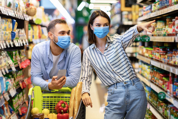 Junge Familie maskiert mit Handy im Supermarkt einkaufen - Foto, Bild