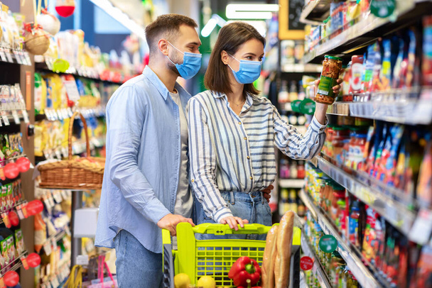Молодая пара в масках для лица в супермаркете - Фото, изображение