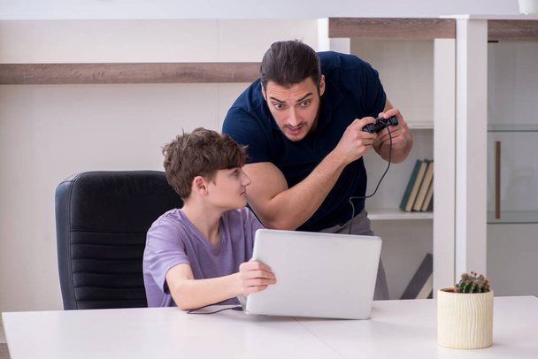 Young father and schoolboy playing computer games at home - Photo, Image