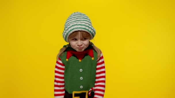 Noel Elf kılığında dağılmış bir kız çocuğu Noel Baba yardımcı kostümü başparmağını aşağıda tutuyor ve hoş olmayan hareketler gösteriyor. - Video, Çekim