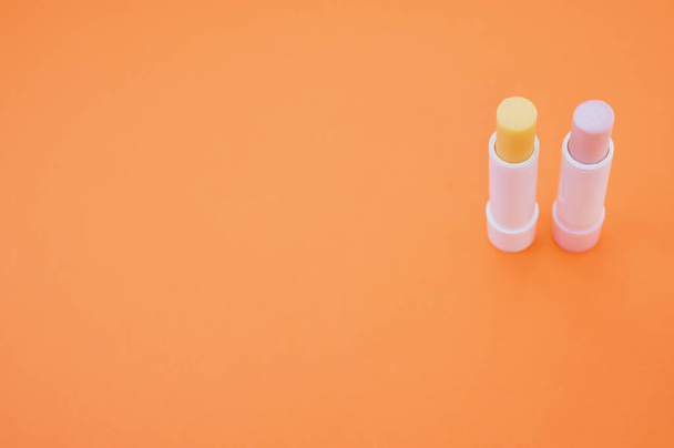 A closeup shot of hygienic lipsticks isolated on orange background - Foto, imagen