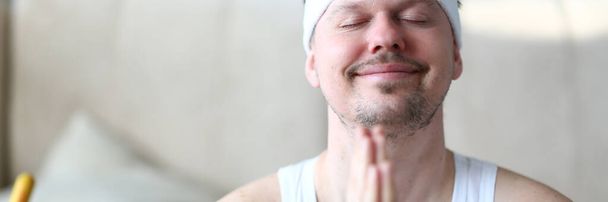 Jeune homme souriant pratiquant le yoga à la maison - Photo, image