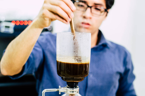 Професійна кавоварка - бариста за допомогою сифону варить гаряче еспресо у кав "ярні.. - Фото, зображення