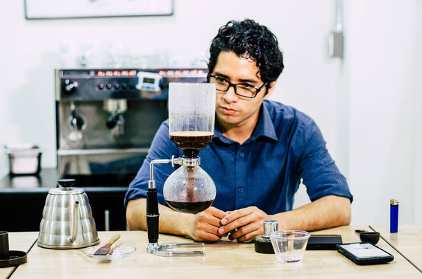 Cafetera profesional - Barista usando sifón de café elaborando café expreso caliente en la cafetería. - Foto, Imagen