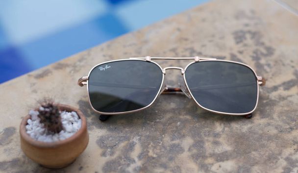 lunettes dorées sur le bord de la piscine bleue - Photo, image