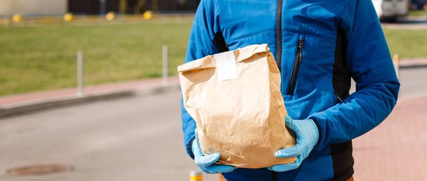 Livraison homme tenant sac en papier avec de la nourriture, livraison de nourriture homme dans un masque de protection - Photo, image