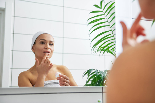 Отражение в зеркале женщины с женской гигиенической помадой на губах - Фото, изображение