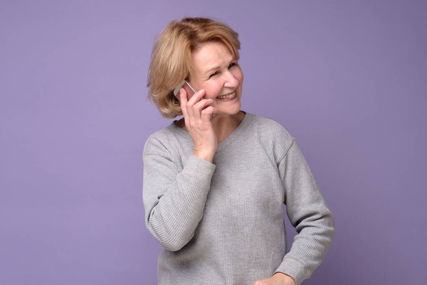 Зріла біла жінка сміється під час розмови на мобільному телефоні
 - Фото, зображення