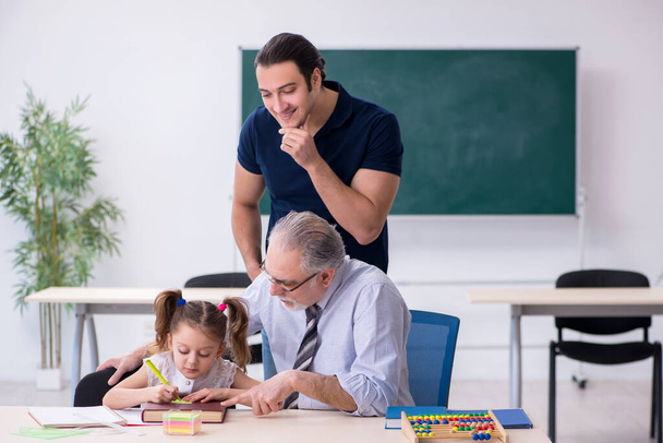 Fiatal szülő, idős férfi tanár és kislány az osztályteremben - Fotó, kép