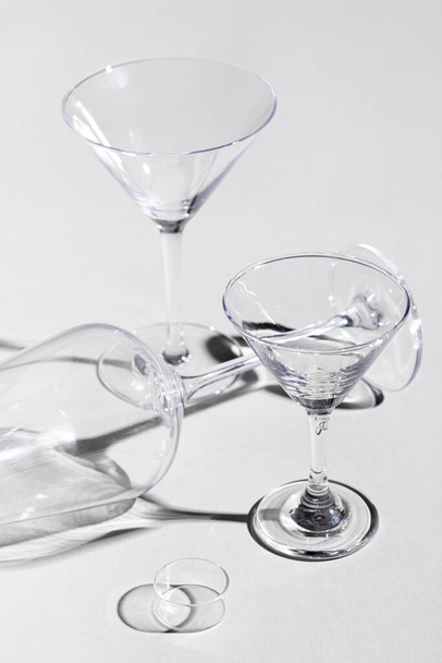A closeup of martini and wine glasses on white surface with shadows - Φωτογραφία, εικόνα