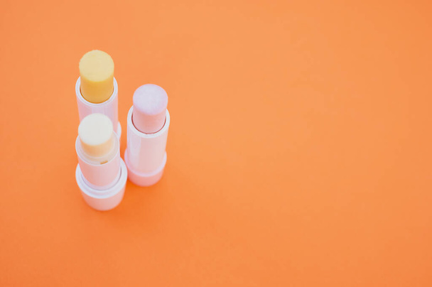 A closeup shot of hygienic lipsticks isolated on orange background - Fotó, kép