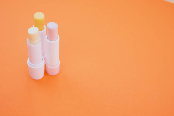 A closeup shot of hygienic lipsticks isolated on orange background - 写真・画像