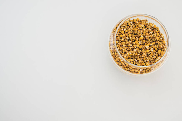 A closeup shot of bee pollen in a transparent bowl on a gray background - Photo, image
