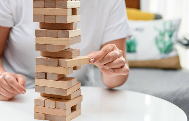 A selective focus closeup of a female holding a piece of a tower of wooden blocks-concept business stability - Photo, image
