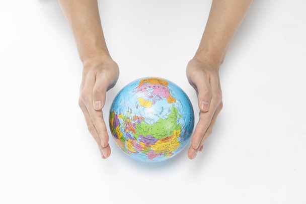 A closeup shot of hands protecting the globe on a white background - environmental concept - Fotoğraf, Görsel