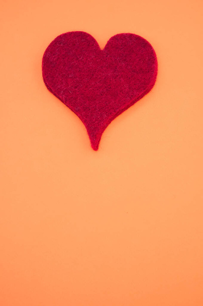A vertical top view of a red heart on orange background for a copy space - Photo, image