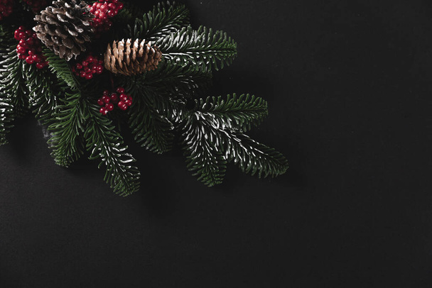 A top view shot of pine branches with cones on a black background - concept of Christmas - Valokuva, kuva