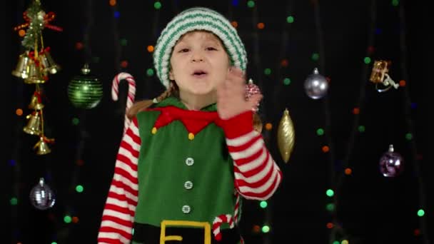 Kind Mädchen in Weihnachtselfe Weihnachtsmann Helfer Kostüm bläst Luftkuss isoliert auf schwarzem Hintergrund - Filmmaterial, Video