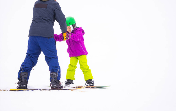 At Cold Winder Day at Mountain Ski Resort Father Teaching Little Daughter Snowboarding - Foto, imagen