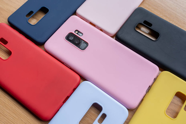 A high angle shot of a cellphone and colorful protective cases on a wooden surface - Foto, immagini