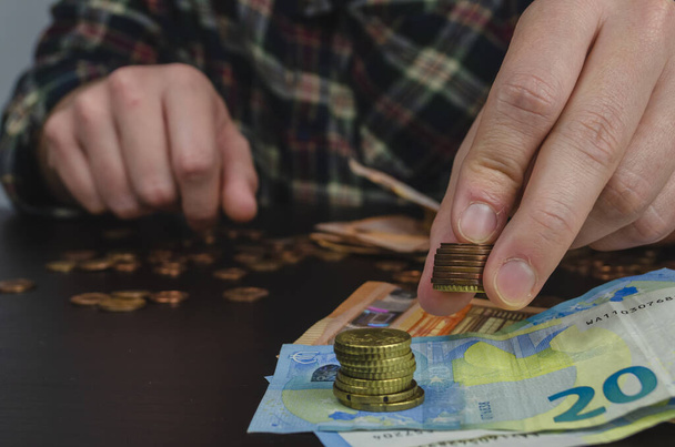 A selective focus shot of a person counting euro banknotes and coins - Фото, изображение