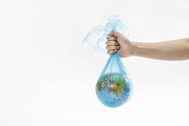 A closeup shot of a hand holding the globe in a plastic bag - environmental concept - Photo, Image